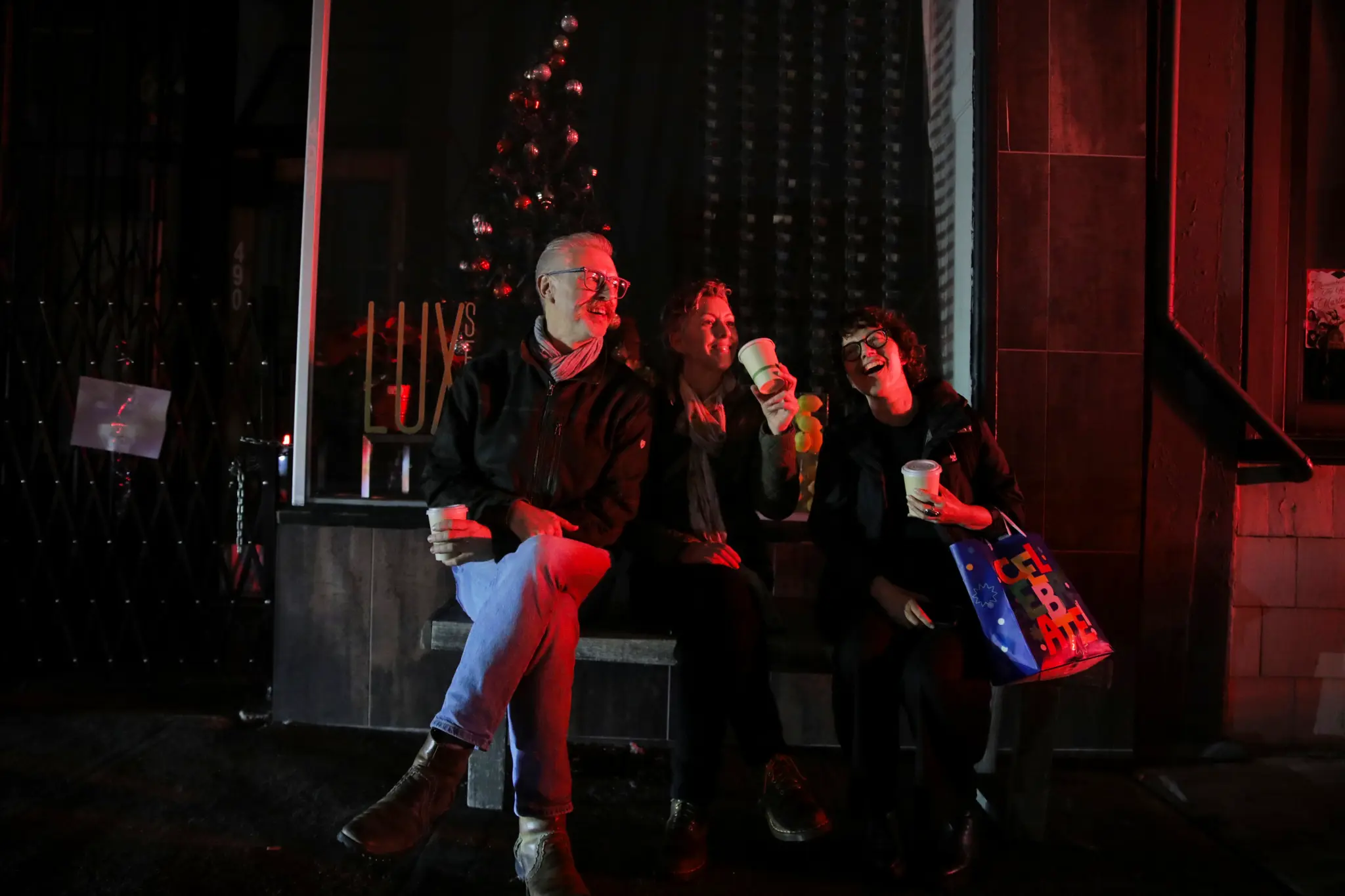San Francisco residents sit outside a closed business during a citywide power outage at night.