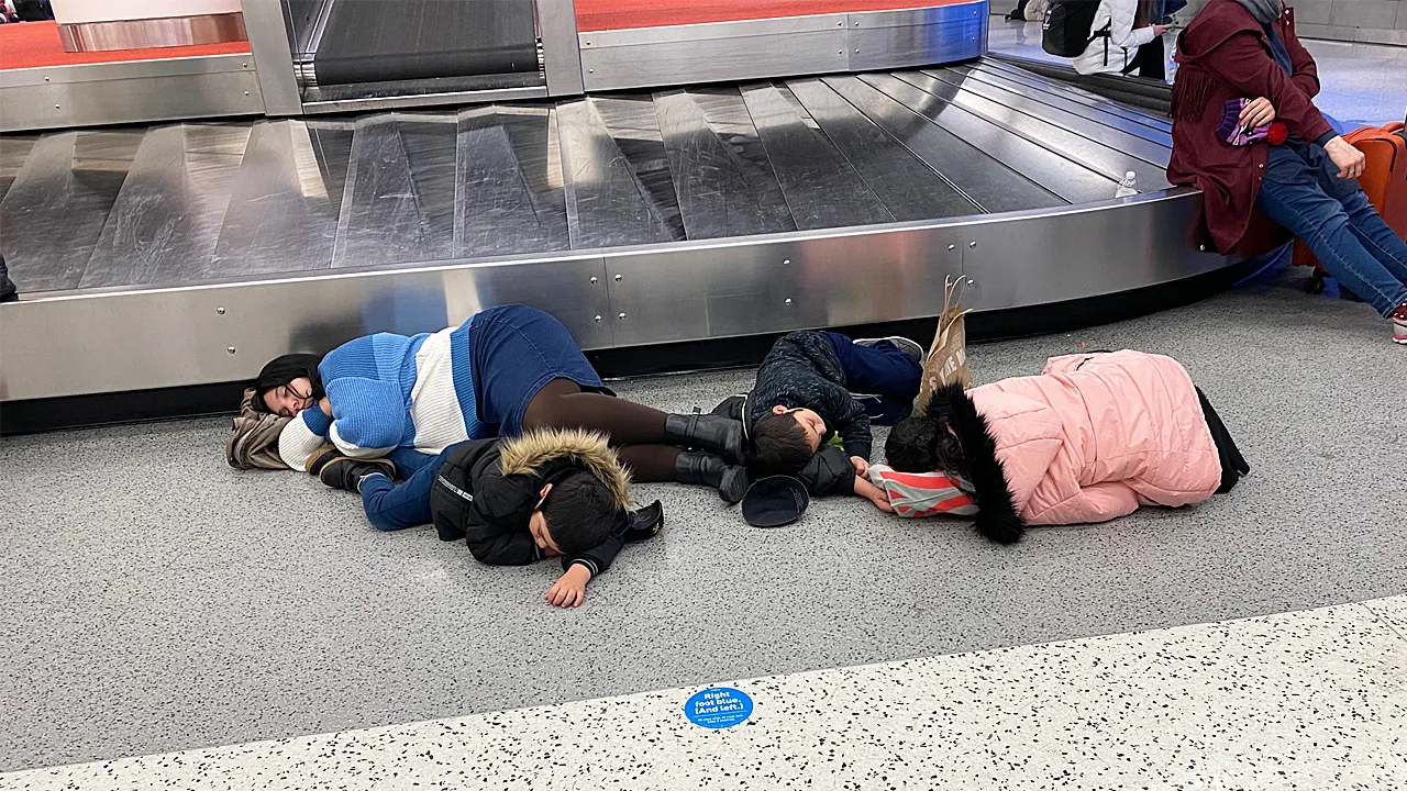 Children and adults rest on the airport floor after flights were canceled due to winter weather.